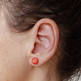 Boucle d'oreille perle ivoire végétal orange sur une oreille Mazonia