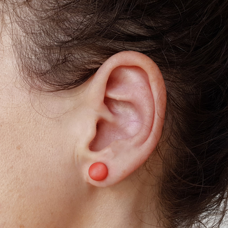 Boucle d'oreille perle ivoire végétal orange sur une oreille Mazonia